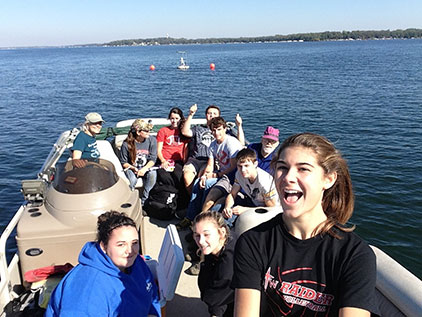 Students and their teacher Dwain Wilmot (in purple cap) cruise around Lake Okoboji with Jane Shuttleworth of Lakeside Lab at the wheel. All Iowa high students are invited to enter the Spirit of the Water High School Essay Contest to share a story of how water inspires them.