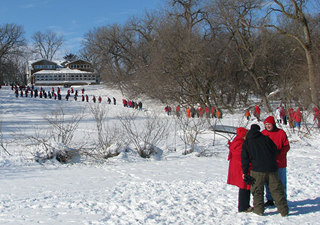 Participants in the former People’s Art event of 2010 are dressed to form a cardinal on the ice of West Lake Okoboji and hike from Lakeside Lab to the frozen lake. Many other activities in the Lakeside Winter Family Fest now take the place of this event.